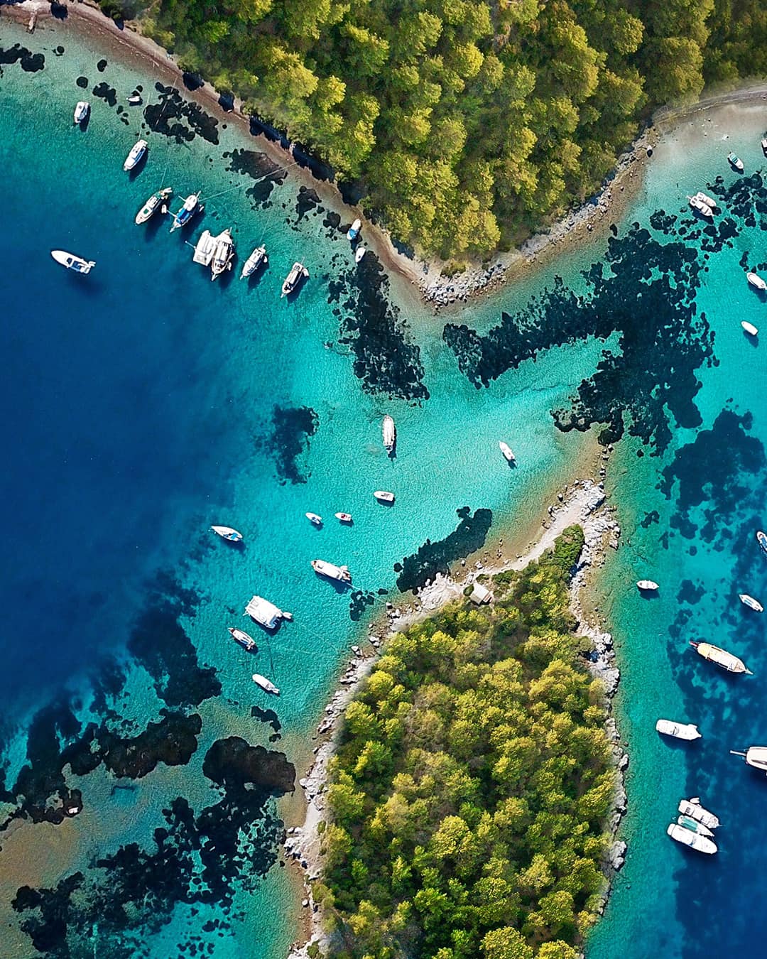 Aerial view of gulets and small boats anchored between pine-covered islets on Turkey’s Turquoise Coast
