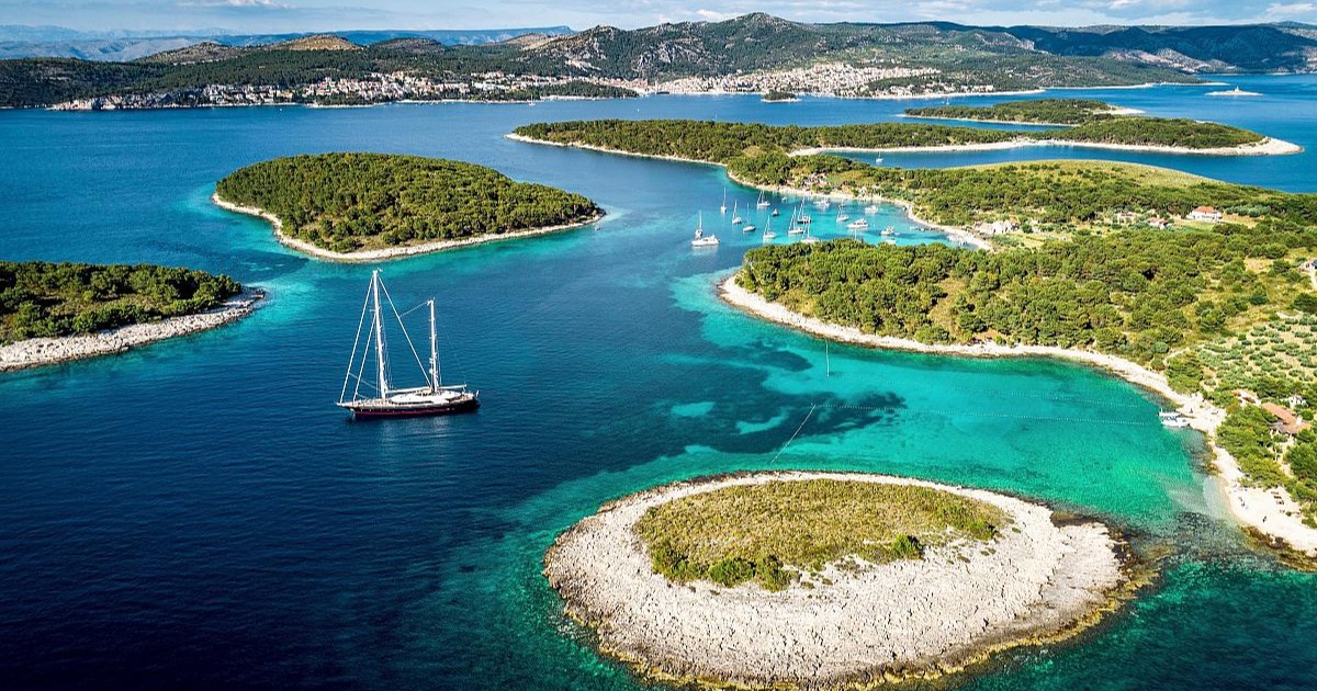 A gulet anchored among the pine-covered islets of the Croatian Adriatic, seen from the air.